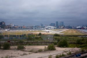An aircraft lines up ready for take-off at London City. Canary Wharf and the O2 are in the background.